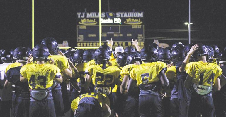 Members of the Sealy Tiger football team surround Head Coach Shane Mobley before beginning the tackling circuit during the Midnight Madness practice at T.J. Mills Stadium Saturday morning. COLE McNANNA