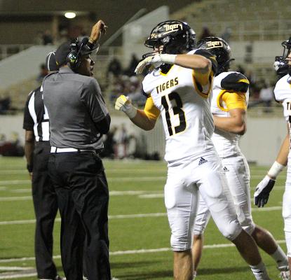 Sealy senior Gage Grigar celebrates his first-half interception with Defensive Backs Coach Ray Dabney Friday night in Aldine. COLE McNANNA