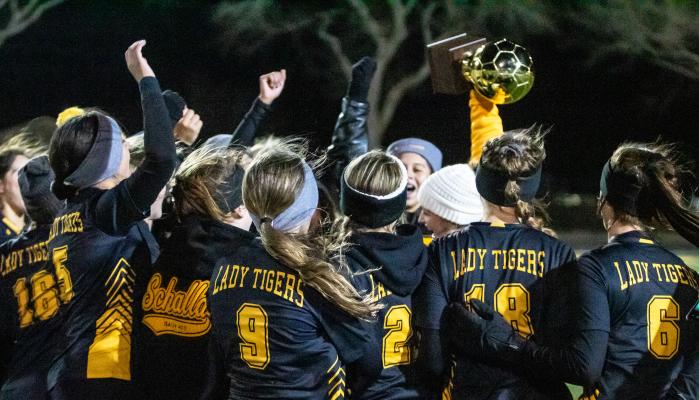 Sealy Lady Tiger Head Soccer Coach Sydney Jones hoists the district championship trophy after last Friday’s 1-0 win over Royal secured the first regular-season title in program history. Sealy will face Rockdale in the postseason opener. COLE McNANNA