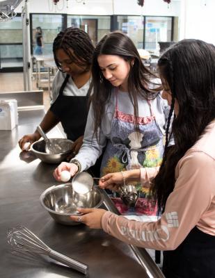 La'Daja Joiner, Grace Tritico and Melina Pacheco Avalos whisk away in the culinary kitchen at Sealy High School during last Thursday’s class. COLE McNANNA