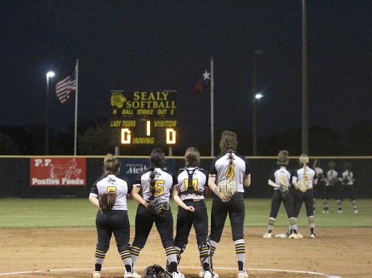The Lady Tiger varsity softball team honors the flag while the National Anthem played to officially open the regular season last Tuesday at Sealy High School. (Cole McNanna/Sealy News)
