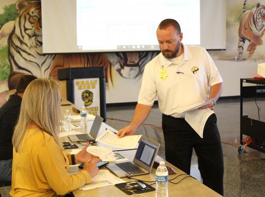 Executive Director of Human Resources and Operations Shawn Hiatt hands out a piece of his presentation regarding policy updates during the regular meeting of the Sealy school board June 23, in the cafeteria of Sealy High School. COLE McNANNA