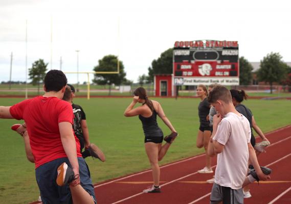 Brazos student-athletes finish up a strength and conditioning workout with a stretch on the track at Cougar Stadium in Wallis Monday, June 28. COLE McNANNA