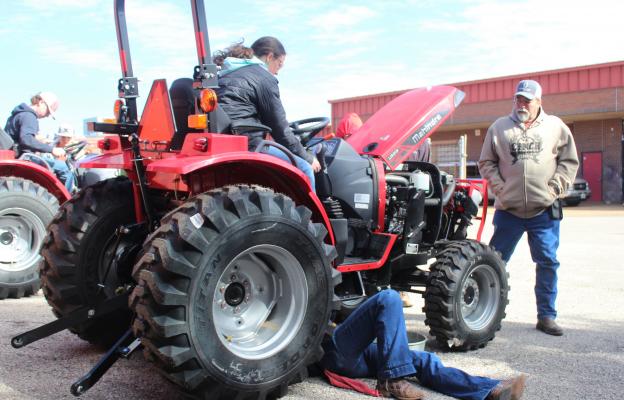HANS LAMMEMAN Samantha Diezi sat on the tractor while Kylee Svinky worked beneath it on their way to an event-best time on the troubleshooting competition last Saturday, Jan. 15 at the 40th Annual Brazos FFA Alumni Tractor Tech Competition in Wallis.