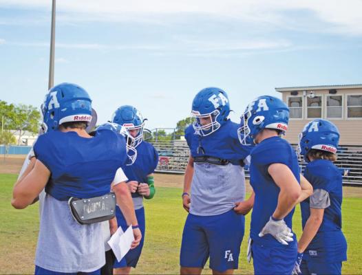 Faith Academy of Bellville Knights players huddle up as they await a play call from head coach Trey Carter during practice Monday Aug. 1. JASON MANAGO-GRAVES