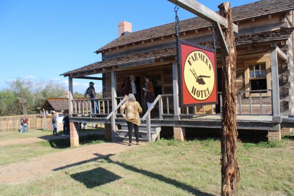 Guests gathered on the porch of the Farmer’s Hotel and tavern during the Grand Opening of the Villa de Austin at the San Felipe de Austin State Historic Site Friday, Nov. 12. HANS LAMMEMAN