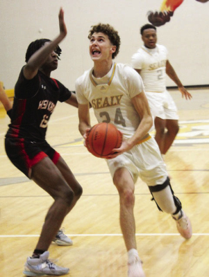 Garrison Ward, with basketball, scored 31 points in Sealy’s two district wins last week. Trailing the play is Sealy’s Javien Grant.