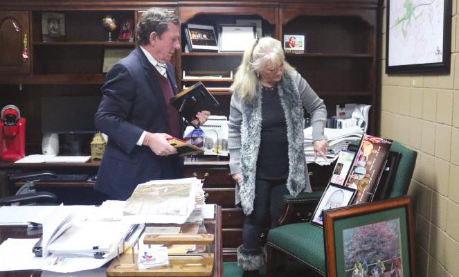City Manager Lloyd Merrell and his wife Marsha begin taking down pictures and packing up his personal belongings in the city manager’s office at city hall Monday night after the city council accepted his resignation and placed him on immediate administrative leave with pay. Photos by Joe Southern