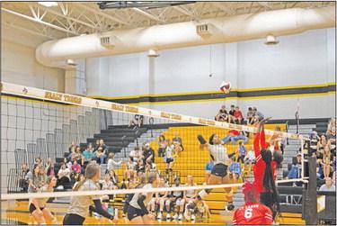 Sealy Lady Tigers senior Jasmyne Joiner stares down the ball as she prepares to send a strike over two towering defenders during the Sealy High School volleyball matchup with Cypress Lakes High School Aug. 23. JASON MANAGO-GRAVES