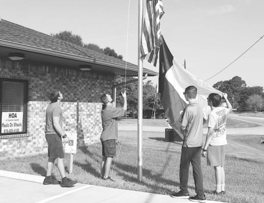 Sealy High School drum majors and boy scouts Pete Ribardo, Ike Konvicka, Tyler Burgess and Zander Crawley helped raise the new flags donated by WoodmenLife to the Meals on Wheels – HOA program Tuesday morning, July 27. PHOTOS BY COLE McNANNA