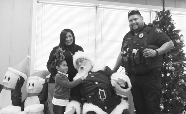 Elizabeth, Emma, and Mario Alcala posed with Santa during last Tuesday’s Kids, Cops, and Christmas event at the Wallis City Hall complex. PHOTOS BY HANS LAMMEMAN