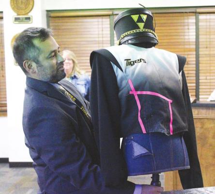 Sealy High School Band Director Oscar Cano shows an example of the 12-year-old band uniforms currently worn by the Roaring Sound from Tiger Town while presenting new band uniforms during the regular school board meeting Jan. 26.