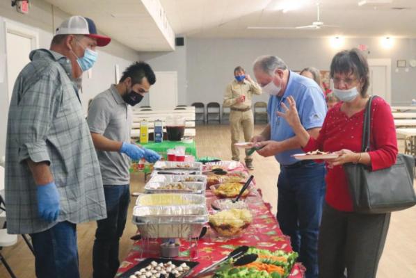 Sealy Mayor Carolyn Bilski, right, and her husband Joe Bilski go through the serving line Thursday at the American Legion hall during the annual holiday mixer hosted by the Sealy Chamber of Commerce.