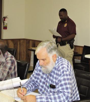 San Felipe Police Chief David Randle presents his monthly report to San Felipe de Austin Town Council. In foreground, Alderman Michel Elliot. PHOTO BY MARCIE ELLIS
