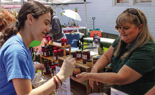 Elinana Cantu, left, scoops a sample of chocolate honey from Barbra Esquivel, owner of Craz E Bees, during the Honeybee Jubilee, Saturday, May 2, at St. John Luthern Church in New Ulm. ALL PHOTOS BY THE CITIZEN | EVAN HALE