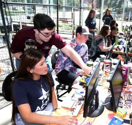 Bast Schellhorn (standing left) helps a cybersecurity camper with programming.