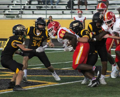 The Sealy Tiger defense, including Richard Hahn (25), Jeffrey Neu (34) and Haden Wernecke (14) converge on Stafford running back Jamaal Wiley in the first quarter of non-district play at T.J. Mills Stadium Friday. COLE McNANNA