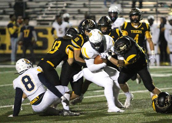 A streak of Tigers including Gage Grigar (13), Thomas Clark (10) and Richard Hahn (25) converge on La Marque quarterback Armond Robinson for a gang tackle in the second half of Sealy’s home finale Friday night. COLE McNANNA