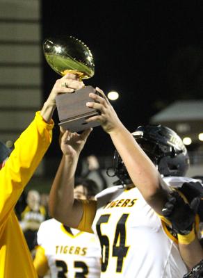 Tiger Head Football Coach Shane Mobley hands off the Bi-District Championship trophy to Sealy senior Robert Gaytan after the Tigers beat Silsbee 21-19 in the first round of the playoffs Friday night at Thorne Stadium. COLE McNANNA