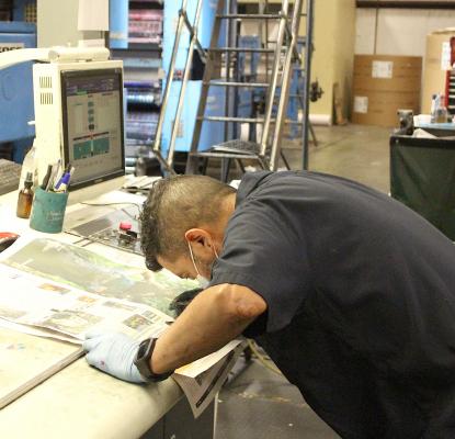 Press Machine Operator Raymond Chavana goes through a quality check on the print edition of a Granite Publication product in Taylor Feb. 18. (Cole McNanna/Sealy News)