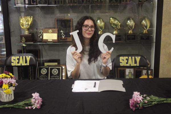 Ria Torres holds up the initials of Jacksonville College after putting pen to paper.