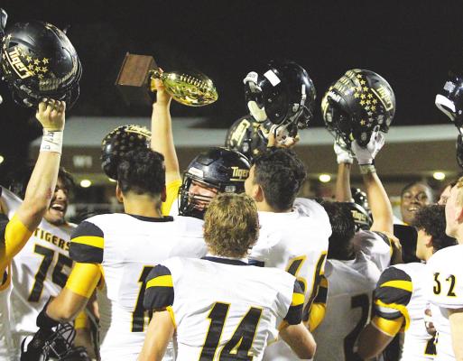 Sealy senior Robert Gaytan hoists the bi-district trophy after the Tigers’ 21-19 win over Silsbee in the first round of the playoffs last Friday at W. W. Thorne Stadium in Aldine. COLE McNANNA