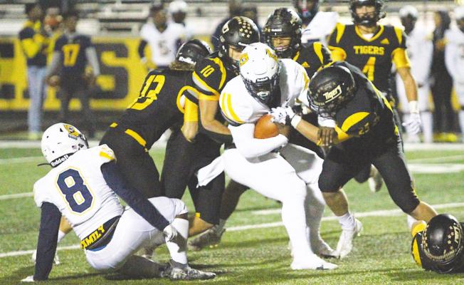 A streak of Sealy Tigers including Gage Grigar (13), Thomas Clark (10) and Richard Hahn (25) converge on La Marque quarterback Armond Robinson for a gang tackle in the second half of Sealy’s home finale Friday night. COLE McNANNA