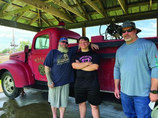 Wallis Fire Chief Clay Englebracht and Patrick and Tracy Prejean volunteer to clean up the historic Wallis Fire Truck last week. COURTESY PHOTO