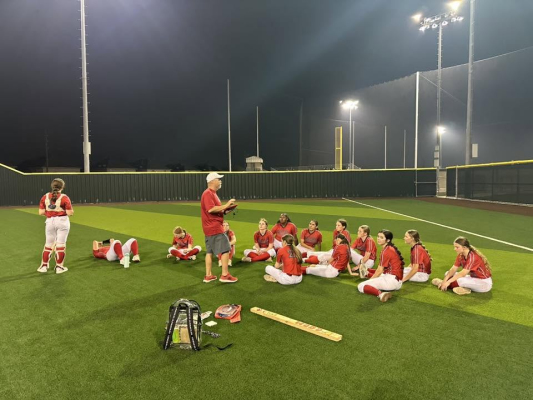 Coach talks to softball players.