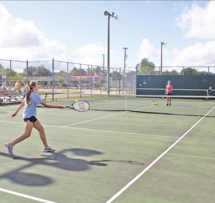 Athletes work on their serve at tennis camp