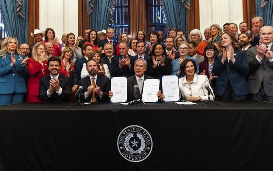 Governor Greg Abbott is flanked by Senator Bryan Hughes, Senator Lois Kolkhorst, Representative Cole Hefner, Representative Janie Lopez, Representative Angelia Orr, and additional members of the Texas Senate and House of Representatives during the ceremony