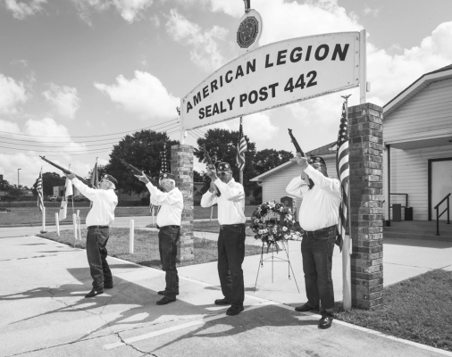 Veterans Joe Marusik, Charles Toman, Walter Mock and Dave Littman hold up rifles in a line for an honorary fire during a Memorial Day ceremony, Monday, May 25, at the Sealy American Legion Hall.