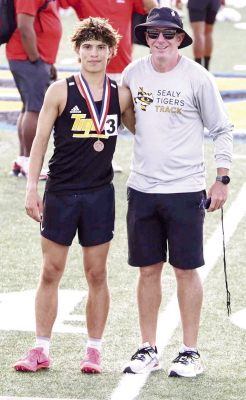 Gavin Almaguer sports his medal with Sealy Track Coach Val Eschenburg after his race. PHOTO BY WILSON CHANEY