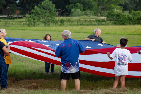 Sealy community members hoist up a large American flag for the national anthem at the Faith, Family and Fireworks event, Saturday, July 4, at Christian City Fellowship in Sealy.