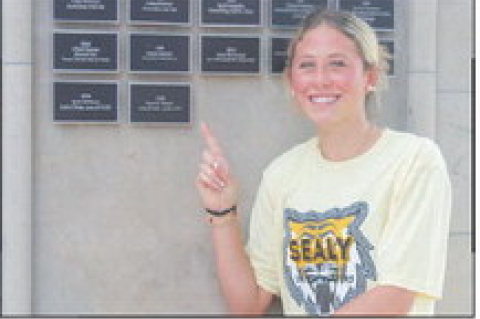 Ryanne Meyer points at her newly unveiled plaque on the Sealy Wall of Champions on Thursday, Aug. 6, at Sealy High School. SEALY NEWS | EVAN HALE