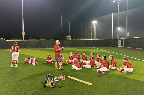 Coach talks to softball players.