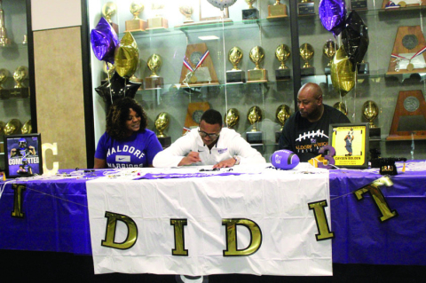 Caysen Bolden signs to commit to Waldorf University with his mother Cassie Morris (left) and his father Jason Bolden (right) by his side. SEALY NEWS | EVAN HALE